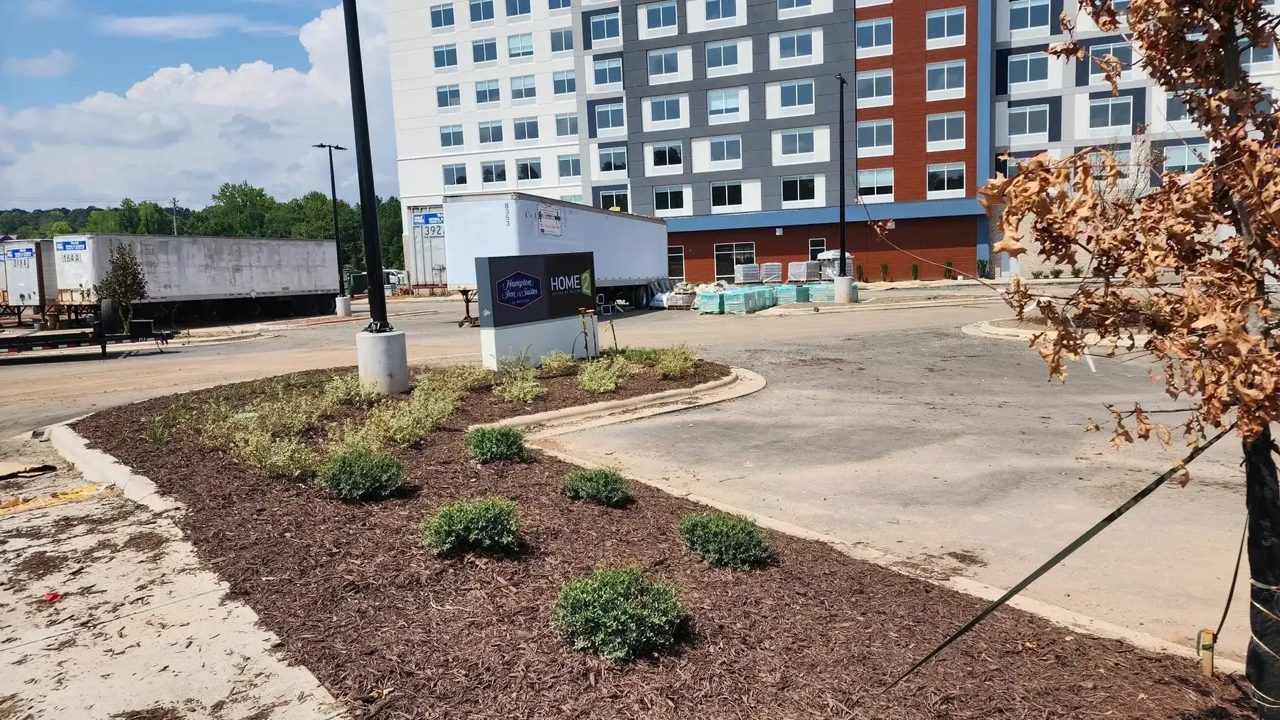New shrub beds and mulch along a commercial parking area in front of a hotel