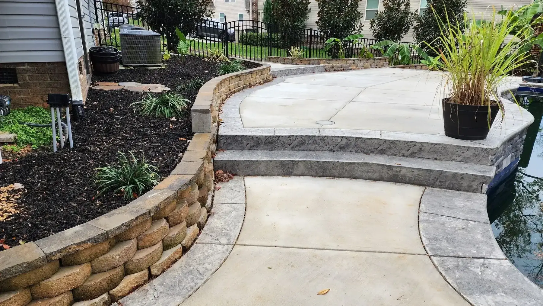 Curved block seat wall with new planting beds and mulch around a concrete patio